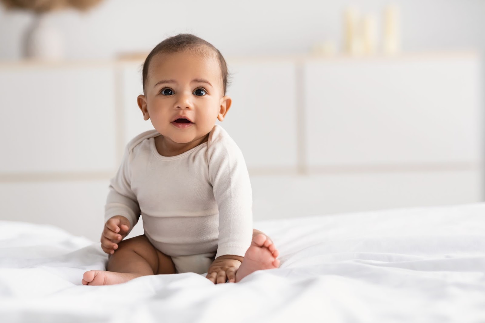 Smiling baby boy sits up while looking at camera.