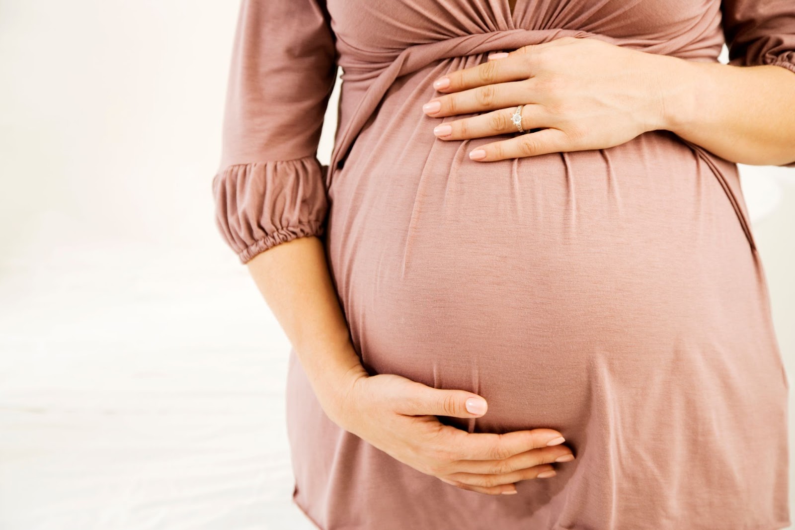 Woman holding her pregnant belly after using a pregnancy belt.